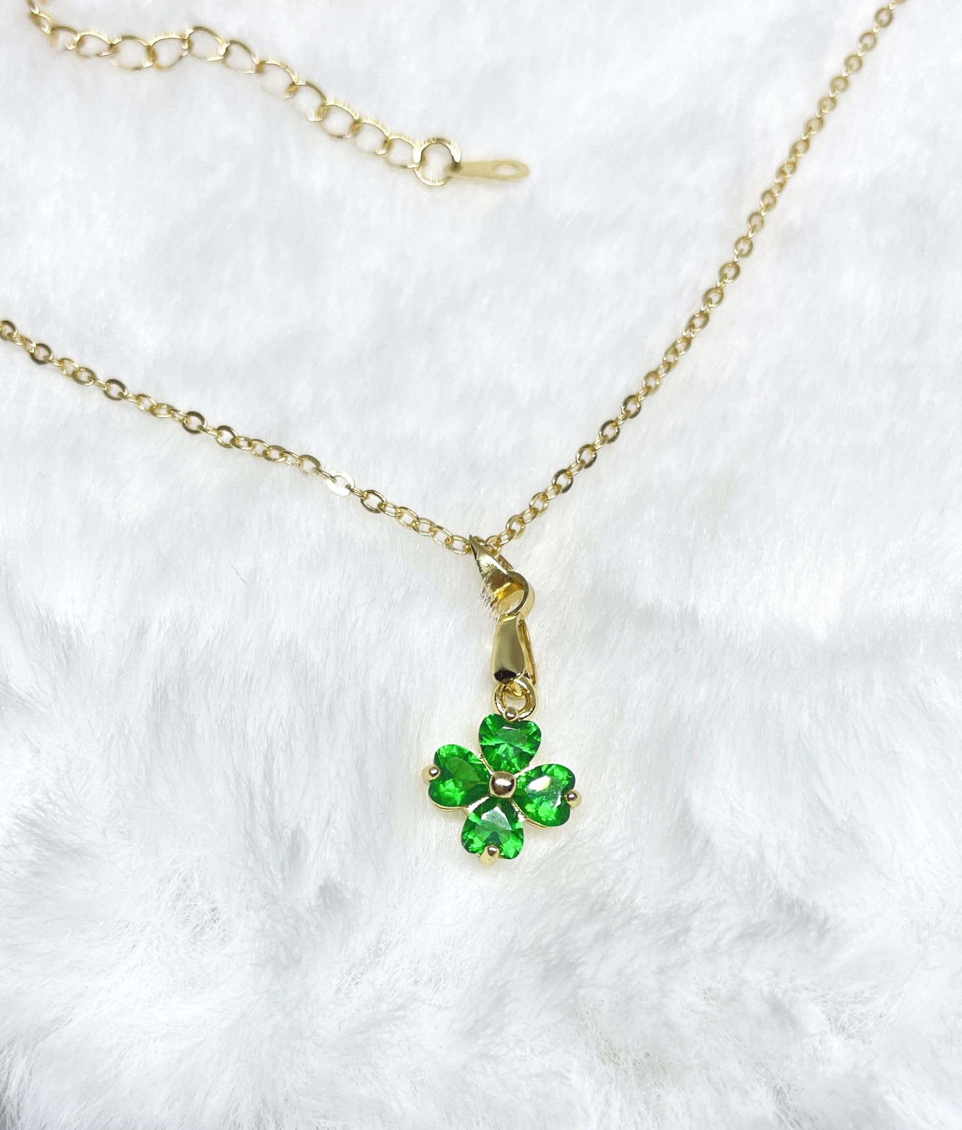 A gold necklace with a green four-leaf clover pendant.