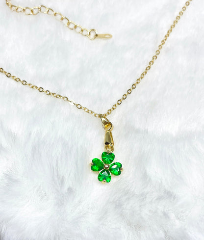 A gold necklace with a green four-leaf clover pendant.