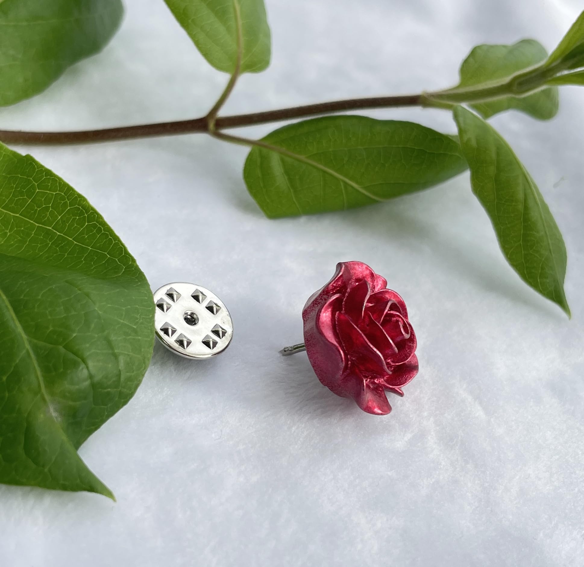 A red rose-shaped earring and silver backing