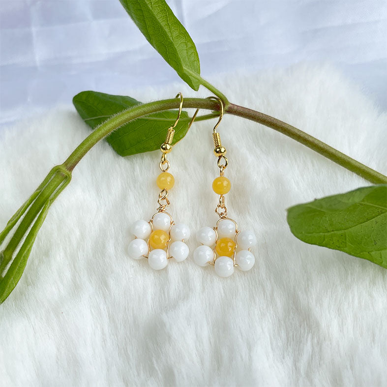Pair of gold earrings with yellow and white daisies.